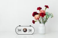 Kaboompics - Black-and-White Flip Desk Clock Beside a White Vase of Red, Pink and Mint Carnations