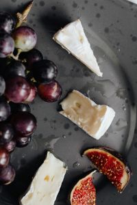 Kaboompics - Camembert Wedges with Grapes and Figs on a Dark Plate