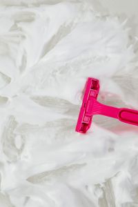Kaboompics - Pink Razor Lying in White Shaving Foam, Top-Down Grooming Still Life