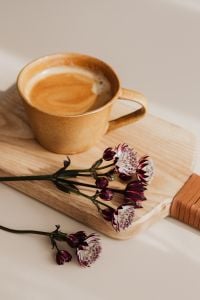 Coffee and Astrantia (Great Masterwort) Still Life with Latte in a Ceramic Cup on a Wooden Board