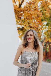 Kaboompics - Smiling Woman with Champagne beside White Wall and Autumn Foliage