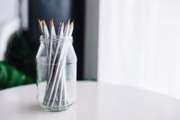 Kaboompics - Patterned Pencils in a Clear Glass Jar on White Desk with Soft Greenery and Copy Space