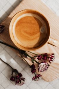 Kaboompics - Top-Down Coffee Cup with Astrantia Flowers on a Pale Wooden Board