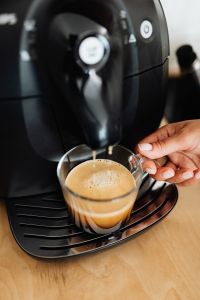 Kaboompics - Black Espresso Machine Brewing Coffee into a Glass Cup for a Home Coffee Routine