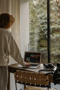 Kaboompics - Woman Reviewing City Images on Laptop at Window Desk