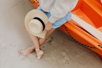Kaboompics - Woman Holding a Straw Sun Hat While Sitting on an Orange Kayak at the Beach