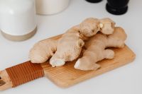 Kaboompics - Whole Ginger Roots on a Wooden Cutting Board with a Handheld Grater