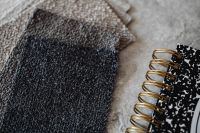 Kaboompics - Layered Black and Neutral Bouclé Upholstery Fabric Swatches Beside a Notes Notebook