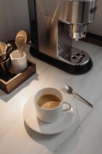 Kaboompics - White Espresso Cup with Crema Beside Coffee Machine