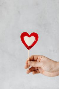 Kaboompics - Hand Holding Small Red Heart Lollipop With Copy Space