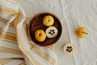 Kaboompics - Wooden Bowl of Whole and Cut Japanese Quince with Loose Slices on White Linen