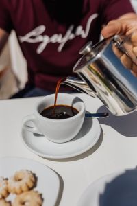 Pouring coffee into a cup. Silver kettles, Italian cookies.