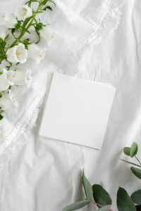 Kaboompics - White Linen Stationery Mockup with Blank Card, White Blossoms and Green Foliage