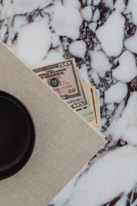 Kaboompics - Dollar Bills Partly Under Linen on White Marble with Black Bowl