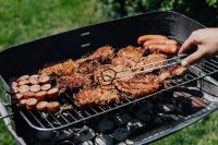 Kaboompics - Hand Turning Pork Neck Steaks and Sausages with Tongs on an Outdoor Charcoal Barbecue