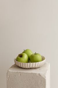 Kaboompics - Close Arrangement of Three Green Apples in a Ribbed Ceramic Dish on Textured Stone Block