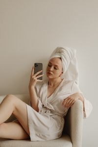 Kaboompics - Woman in a White Robe Taking a Skincare Selfie with Eye Patches at Home