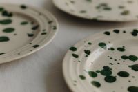 Kaboompics - Green Splatter Ceramic Plates in a Soft Focus Linen Still Life