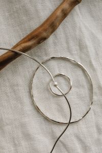 Kaboompics - Abstract Silver Circular Jewelry with a Pearl on Linen