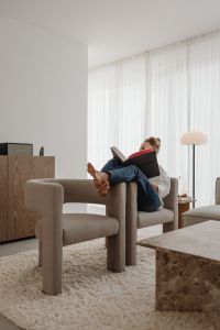 Kaboompics - Woman Reading a Book in a Neutral Armchair with Her Feet Up