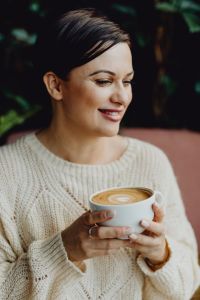 Kaboompics - Woman Enjoying a Latte at a Cozy Cafe Table with a Flower Bouquet