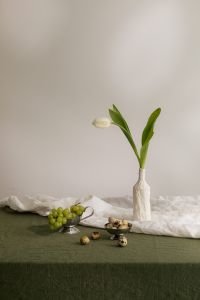 Kaboompics - Minimal Easter Table Still Life with White Tulip, Green Grapes and Quail Eggs on Textured Linen, Spring Floral Food Background