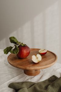 Kaboompics - Red Apple Halves and Whole Fruit on a Round Wooden Board, Simple Recipe Styling