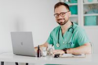 Kaboompics - Smiling Doctor Using Laptop in Medical Office