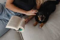 Kaboompics - Woman Petting Her Small Dog Beside an Open Book