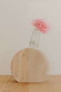Kaboompics - Soft Pink Flower Blur Behind Ribbed Glass with Travertine Accent, Neutral Background
