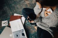Kaboompics - Woman reading magazines on the floor while enjoying hercup of tea