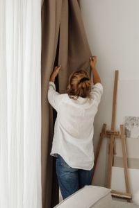 Kaboompics - Woman Opening Curtains in a Bright Living Room