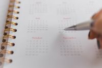 Kaboompics - Silver Pen Pointing at July and August Dates in a Pink Planner, Calendar Close-Up