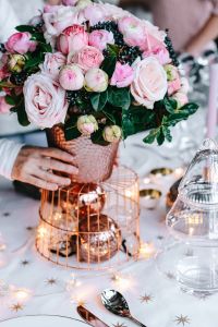 Hands Setting an Elegant Christmas Table with Pink Flowers and Candlelight