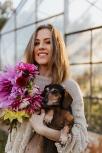 Kaboompics - Woman With Dachshund Beside Multicolored Dahlias