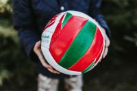 Kaboompics - Red, White and Green Volleyball Held Outdoors, Close-Up Sports Equipment Photography