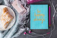 Kaboompics - Blue notebook with a pink iPhone, headphones and a sweet bun