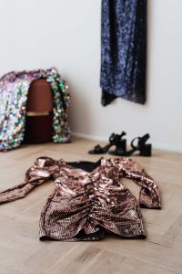 Kaboompics - colored sequin dresses and boots lie on a wooden parquet, blue dress hang on the white wall