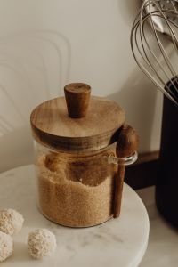 Kaboompics - Brown Sugar in a Glass Pantry Jar with Wooden Lid, Marble Stand and Whisk, Vertical Kitchen Background