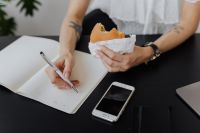 Kaboompics - Freelancer Writing in Notebook During Meal Break