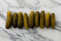 Kaboompics - Row of Pickles Arranged on White Marble Background with Copy Space
