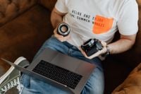 Kaboompics - Photographer Reviewing Camera Equipment beside an Open Laptop