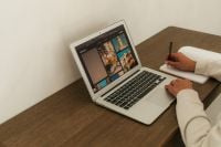 Kaboompics - Laptop Desk Setup With Notebook and Hand Taking Notes
