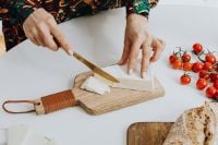 Kaboompics - Woman Cutting Cheese on a Wooden Board
