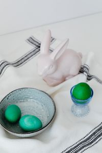 Kaboompics - Ceramic Easter Bunny and Green Egg in a Blue Glass Egg Cup