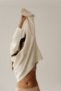 Kaboompics - Woman Holding a Ribbed Cream Sweater Over Her Face in a Neutral Fashion Portrait