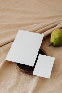 Kaboompics - Portrait Pear and Two Blank Business Cards on a Dark Wooden Plate