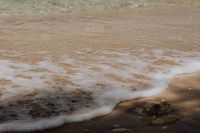 Kaboompics - Foamy Wave Along Sandy Beach With Coastal Rock