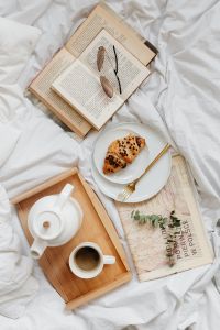 Kaboompics - Vertical Breakfast-in-Bed Flat Lay with Coffee, Croissant, Paperback and Sunglasses