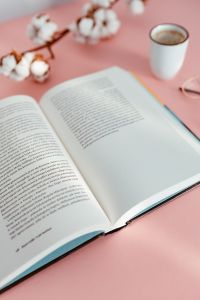 Kaboompics - Open Book with White Coffee Cup and Cotton Stems on Pink Table